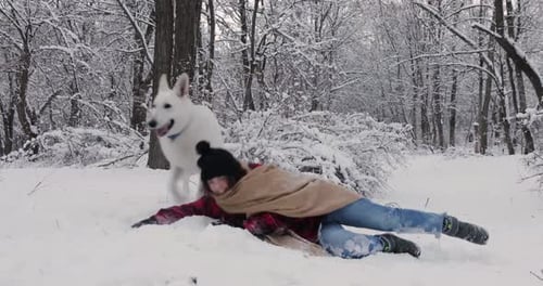 Woman and Dog Play in Snowy Winter Forest