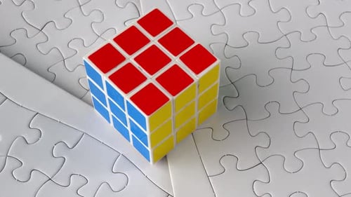 Unsolved Rubik's Cube on White Puzzle Pieces