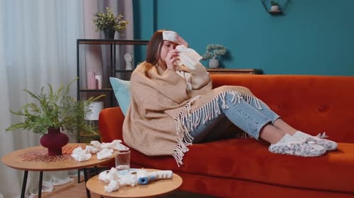 Portrait of Young Woman Suffering From Cold or Allergy in Plaid Lying on Sofa in Living Room at Home