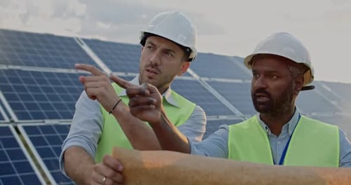 Close Up View of Male Engineers Communcating and Checking Scheme Plan While Standing at Solar Energy