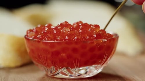 Mixing Red Caviar in Glass Bowl Closeup