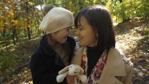 Mother and Child Smiling Together in Autumn Woods