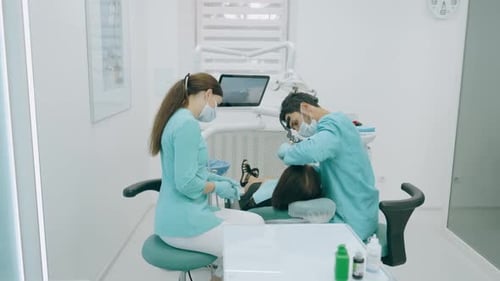Dentist with Nurse and Patient in Dentist Office. A Patient Getting Dental Treatment at Dental