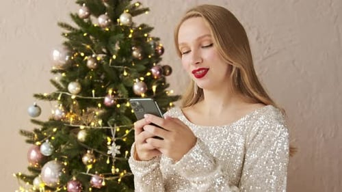 Woman in a shiny evening dress typing message on mobile phone texting sms congratulates friends