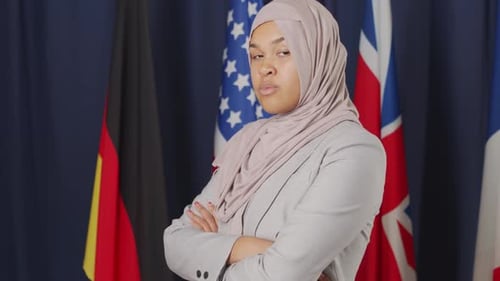 Confident Woman with Hijab Poses in Front of Flags