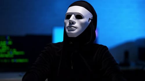 Masked Hacker at Computer in Dark Room