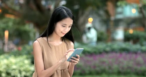 Woman using smart phone and sitting on city park