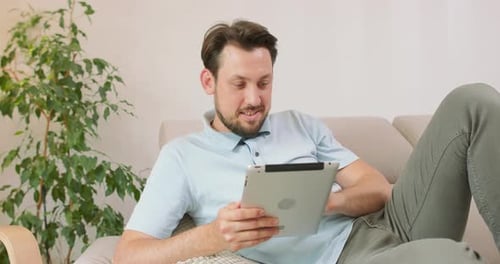 Man Relaxing on Couch Using Tablet at Home