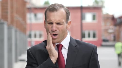 Man in Suit Experiencing Tooth Pain Outside