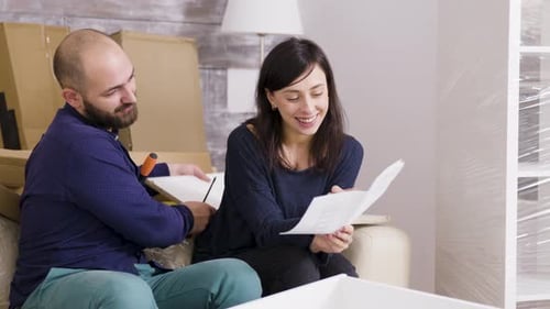 Couple Smiling While Assembling a Shelf in Their New Apartment