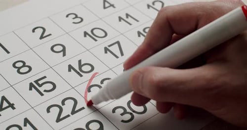 Man's Hand Write Down the 23Th Day on the Paper Calendar Using a Red Pen