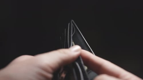 Close-up of a Man's Hands on a Dark Background, One Dollar in His Wallet. Budget and Expenses