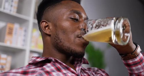 Un homme africain heureux boit de la bière avec bonheur pendant le temps de détente