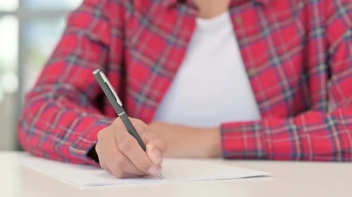 Hände einer afrikanischen Frau beim Schreiben auf Papier