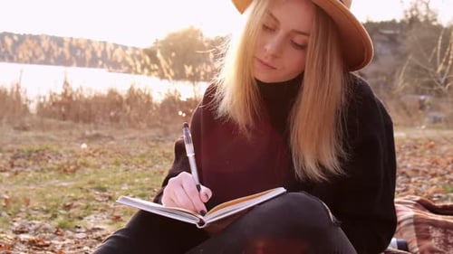 Woman Journaling at Sunset by Lake
