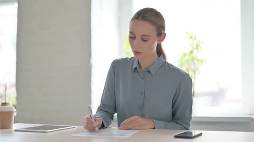Woman Writing on Paper in Office