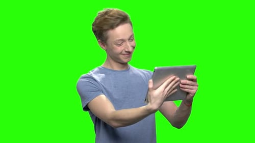 Smiling Young Adult with Tablet on Green Screen
