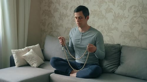 Man Meditating at Home with Prayer Beads