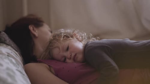 a disgruntled child lies on his mother's chest