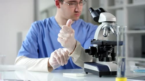 Scientist Adjusts Microscope in a Laboratory