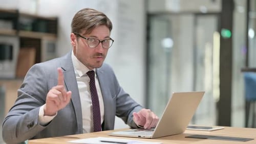 Professional Man Types on Laptop and Raises Finger