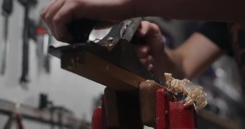 Gitarrenbauer nutzt Handhobel für die Holzverarbeitung in seiner Werkstatt