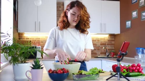 Une jeune femme à la maison dans la cuisine raconte une recette devant la caméra