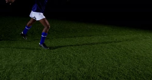 Soccer Player Kicking Ball on Field at Night