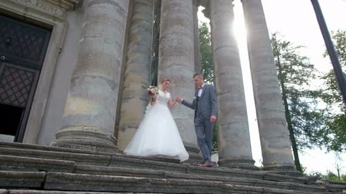 Beautiful Couple of Brides Hugging and Kissing Near Large Columns in the Old Town Wedding Day