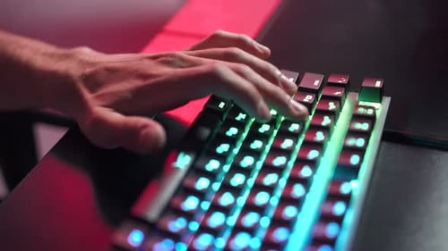 Young Gamer spielt ein Videospiel Nahaufnahme der Hände auf der Tastatur beleuchtete Korallenfarbe und