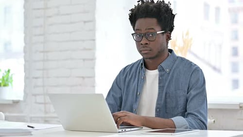Young Adult Smiling and Typing on Laptop