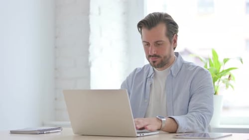 Young Man Working on Laptop in Office