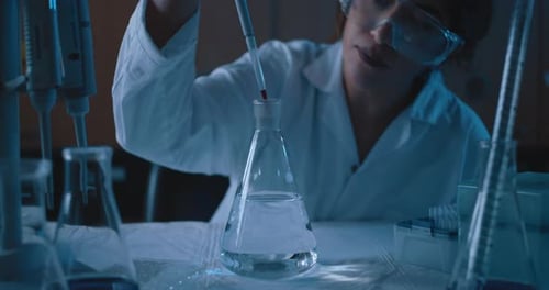 Scientist Mixing Liquids in Glassware in Lab