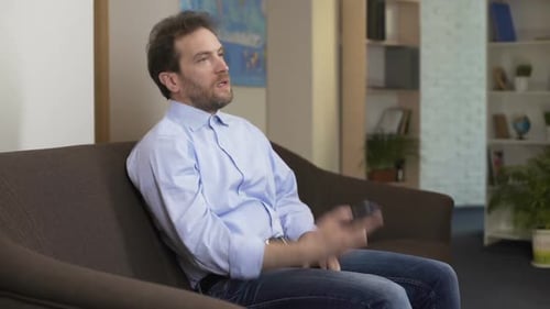 Man Sits and Talks on Smartphone Indoors