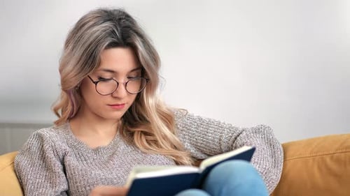 Woman Reading a Book on a Yellow Couch