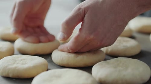 Hands Flattening Fresh Dough on Baking Sheet