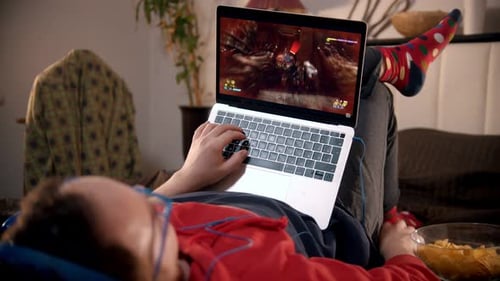 Person Reclining and Playing Video Game on Laptop