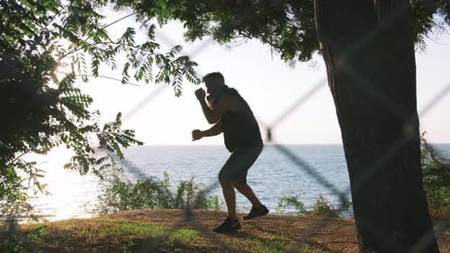 Middle Aged Man with Long Gray Beard Boxing with Shadow in Park During Sunrise Slow Motion