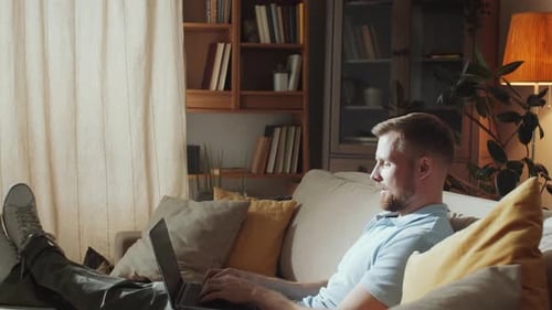 Man Relaxes With Laptop on Couch at Home