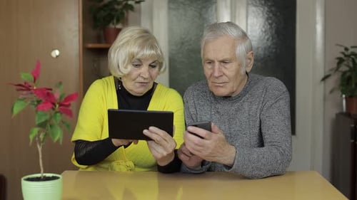 Senior Couple Using Tablet and Smartphone at Home