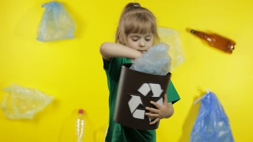 Niña activista recoge paquetes de celofán y los pone en un basurero. Basura, plástico, contaminación natural