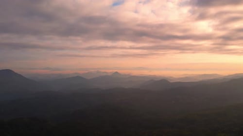 4K Flying through the clouds above mountain tops. Tropical forest with smoke and fog.