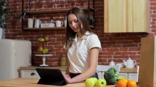 Woman Using Tablet with Fresh Produce in Kitchen