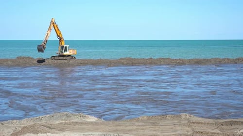 Una excavadora trabaja en la arena de la playa