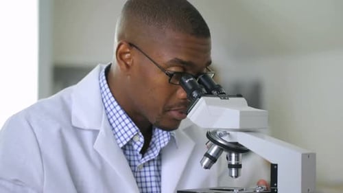 Man Scientist Looking Through Microscope in Laboratory