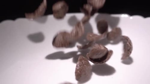 Chocolate Cereal Being Poured Into White Bowl