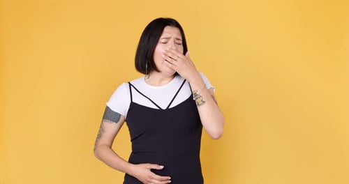 Jeune femme élégante avec des bâillements de tatouage. Hipster ennuyé bâillant et couvrant la bouche