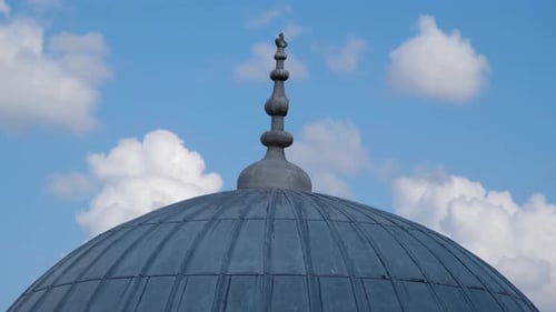 Dome of a Building with Spire and Clouds