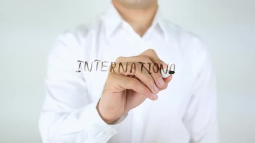 Man Writes "International" on Clear Surface