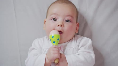 Cute Baby with Rattle Lying on Blanket
